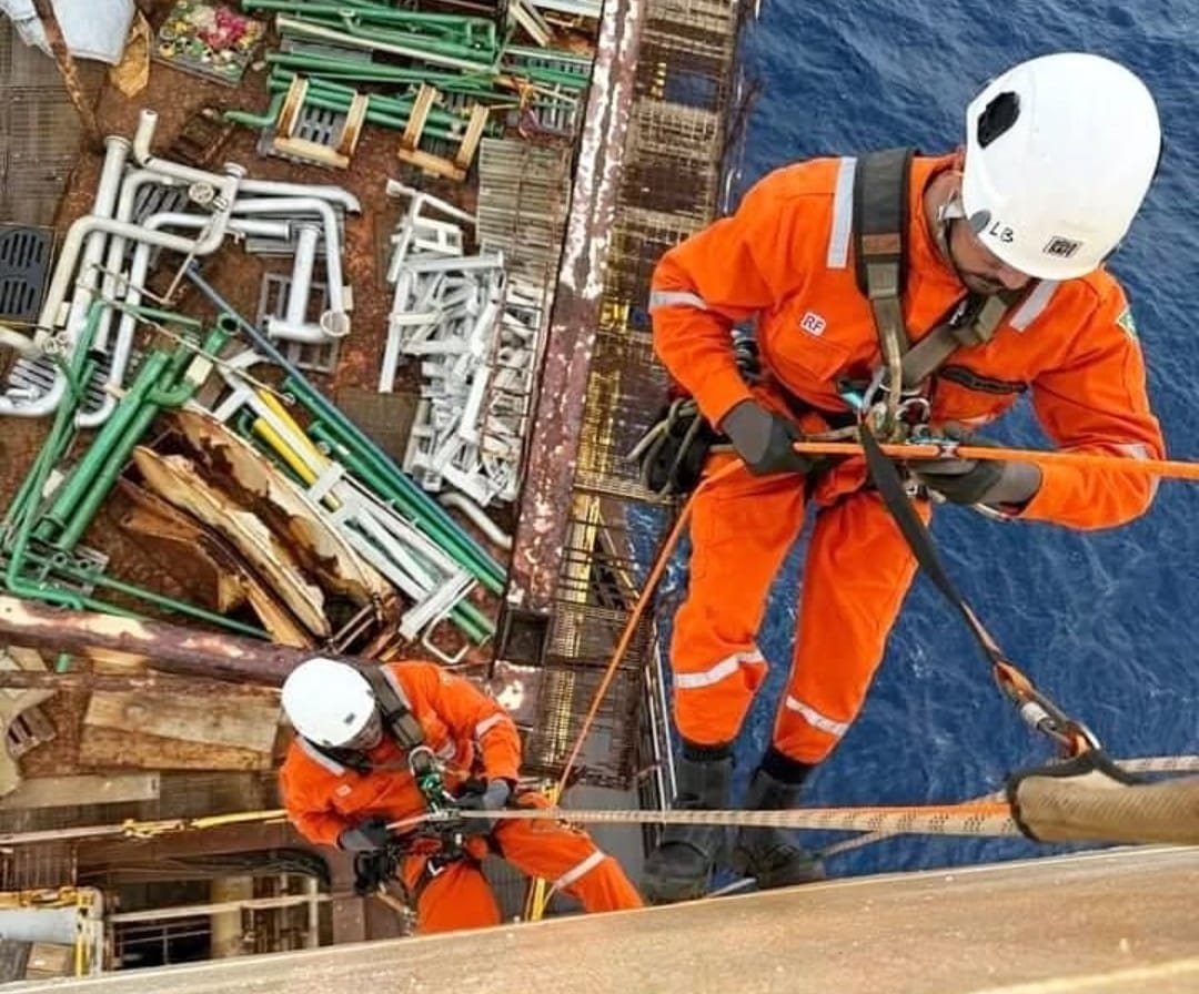 Homens com equipamentos de proteção executandos serviço em industria